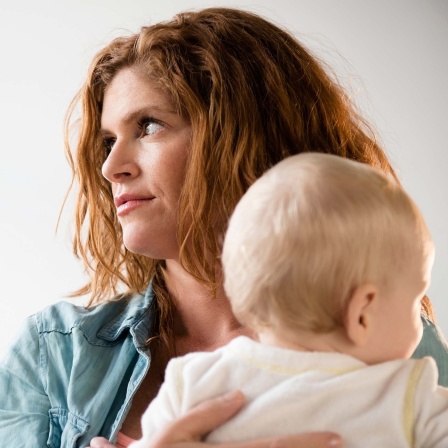 Symbolbild: Eine nicht glücklich schauende Frau hält ein Baby im Arm.