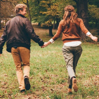 Ein Mann und eine Frau laufen Hand in Hand durch einen Wald.