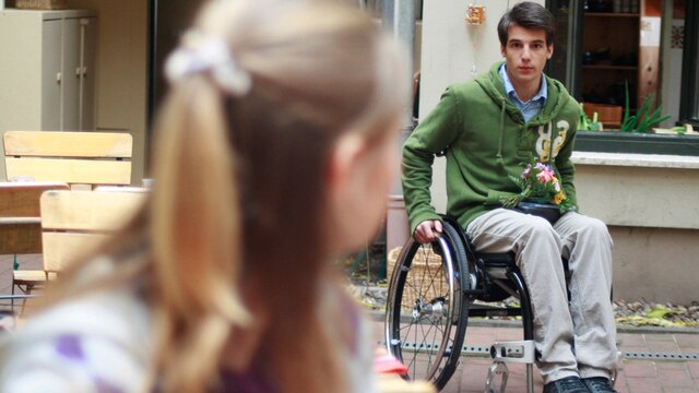 Peter kommt mit seinem Rollstuhl in den Innenhof einer Gaststätte.
