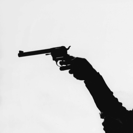 Die Silhouette von einer Frau, die einen Revolver hält.