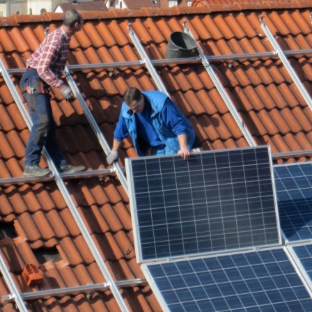 Arbeiter installieren Solarzellen auf einem Dach