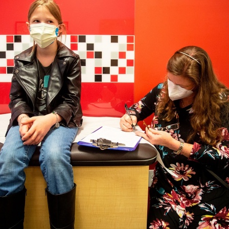 Die zehnjährige Mackenzie Olson sitzt neben ihrer Mutter in einer Kinderarztpraxis und wartet darauf, gegen das Coronavirus geimpft zu werden.