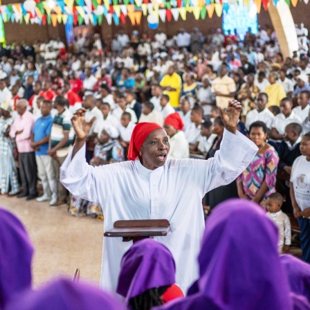 Eine katholische Gemeinde in der Republik Kongo feiert einen Gottesdienst, in der Mitte steht eine Frau im weißen Gewand
