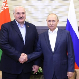 Lukaschenko und Putin schütteln die Hände vor ihren Landesflaggen.