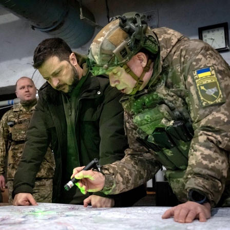 Wolodymyr Selenskyj (M), Präsident der Ukraine, Olexander Syrskyj (r), Kommandeur der ukrainischen Bodentruppen, und Roman Maschowez, stellvertretender Leiter des Präsidialamtes, betrachten eine Landkarte während ihres Besuchs in der Frontstadt in der Region Charkiw. 