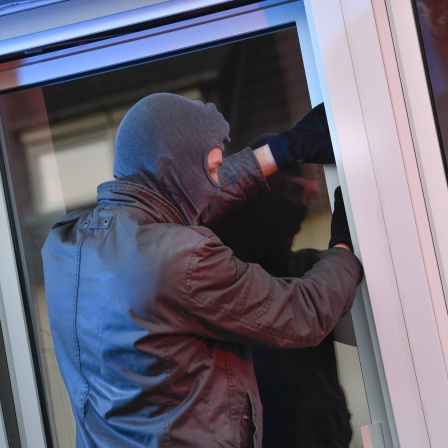 Symbolfoto: ein Einbrecher versucht, durch ein geöffnetes Fenster in eine Wohnung zu gelangen.