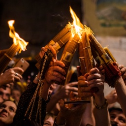 Gläubige halten Kerzen während einer Oster-Zeremonie in Jerusalem in die Luft.