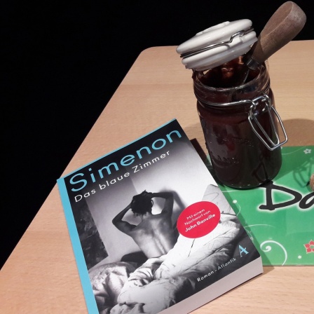 Ein Buch von George Simenon auf einem Tisch mit dem Essen von Folge 17 des Literaturpodcasts "eat.READ.sleep"