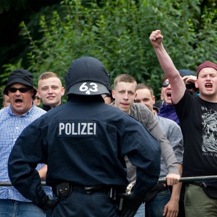 Gegendemonstranten des Neonazi-Aufmarschs in Bad Nenndorf protestieren hinter einer Polizeiabsperrung.