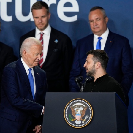 Joe Biden schüttelt Volodomir Selensky hinter dem Rednerpult des NATO-Gipfels die Hand