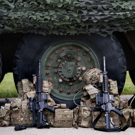 Vor einem Militärfahrzeug liegen Rucksäcke und Gewehre (Bild: picture alliance / ZB | Arno Burgi)