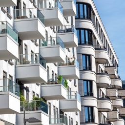 Die Fassade eines weißen modernen Wohnhauses mit vielen kleinen Balkonen.