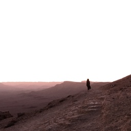 Eine Frau steht in der bergigigen Landschaft der Negev Wüste.