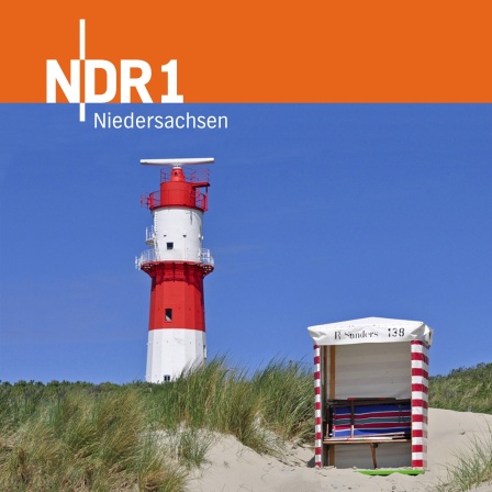 Ein Leuchtturm in den Dünen mit einem Strandkorb davor.