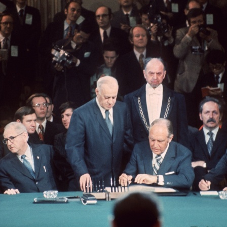 Der amerikanische Außenminister William P. Rogers (M) unterzeichnet am 27. Januar 1973 im Pariser Hotel Majestic das Waffenstillstandsabkommen zwischen den USA und Nordvietnam.