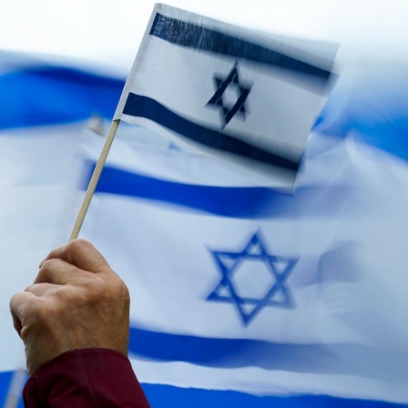 Eine Person hält eine Israel-Flagge auf einer Demonstration. 