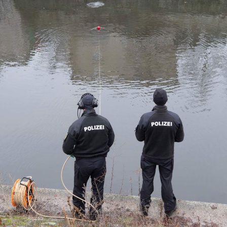 Zwei Polizisten bei der Suche nach Beweisen in einem See. (Quelle: Picture Alliance)