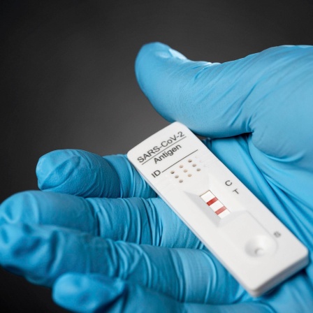 Schutzhandschuh hält Corona Virus Test von erkrankter Person