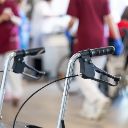 Ein Rollator steht in einem Gemeinschaftsraum eines Pflegeheims.