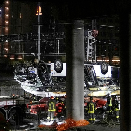 Italienische Feuerwehrleute arbeiten nach einem Busunglück in Venedig an der Unfallstelle. Der von einer Hochstraße gestürzte Bus wird von zwei Kränen geborgen.
