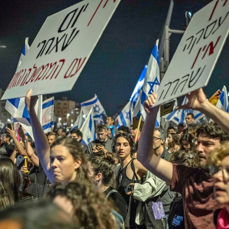 In einer Menschenmenge werden bei einer Demonstration in Jerusalem in Israel Plakate mit regierungskritischem Inhalt hochgehalten.