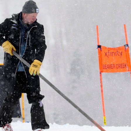 Ein Arbeiter räumt vor der Absage des Weltcup-Abfahrtsrennens den Schnee von der Strecke,