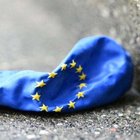Ein Luftballon im design der EU-Flagge liegt luftleer auf dem Boden.