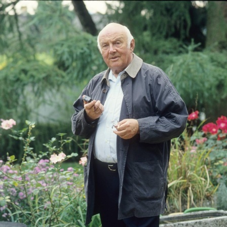 Kinderbuchautor Otfried Preußler steht auf einem Farbfoto von 1993 leger in einem Garten mit einem Diktiergerät in der Hand. 