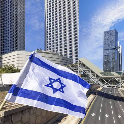 Skyline von Tel Aviv, davor weht eine israelische Fahne (Bild: picture alliance/imageBROKER/elov)