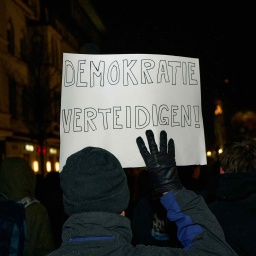 Auf einer Demo in Essen hält eine Person ein Schild mit der Aufschrift: "Demokratie verteidigen"
