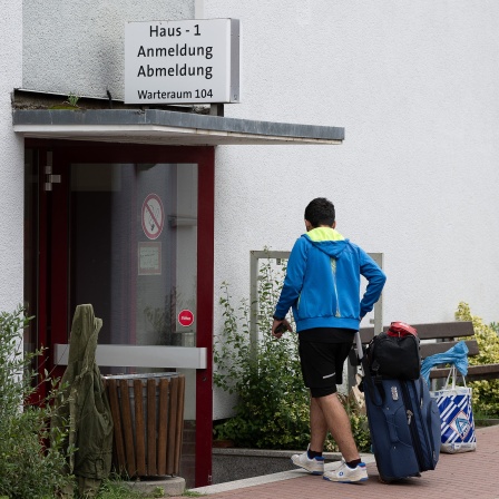 Ein Geflüchteter geht mit einem Koffer in die Anmeldung der Landesaufnahmebehörde Niedersachsen am Standort Grenzdurchgangslager Friedland. 