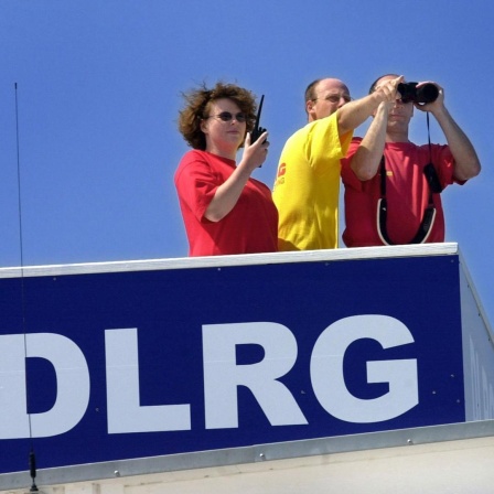 Mit Fernglas und Funkgerät ausgerüstet beobachten eine Rettungsschwimmerin und zwei Rettungsschwimmer einer DLRG-Staffel am 26. Juli 2001 den Strand von Kühlungsborn. 