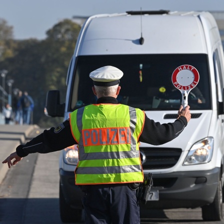 Ein Beamter der Bundespolizei stoppt einen Fahrer eines Kleintransporters bei der Einreise nach Deutschland am deutsch-polnischen Grenzübergang