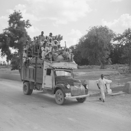 Historisches Schwarzweißfoto von 1947: Flüchtlinge sitzen auf einem mit Möbeln beladenen LKW.