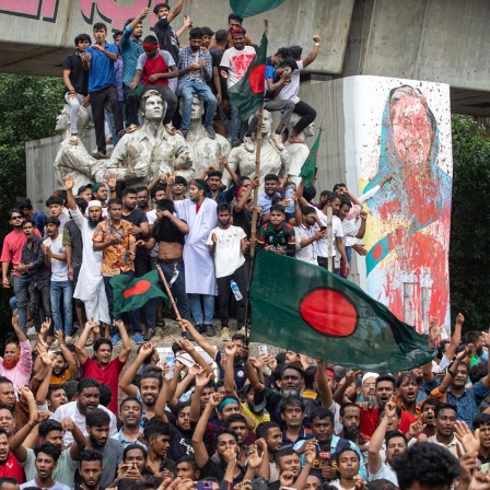 Demonstranten klettern auf ein öffentliches Denkmal und feiern, nachdem sie die Nachricht vom Rücktritt von Premierministerin Scheich Hasina erhalten haben.