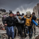 Zivilisten und Mitglieder des syrischen Zivilschutzes führen Such- und Rettungsmaßnahmesuchen in den Trümmern eines zerstörten Gebäudes in Harem durch.