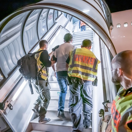 Polizeibeamte führen einen Mann bei seiner Abschiebung auf dem Flughafen Leipzig-Halle in ein Charterflugzeug.