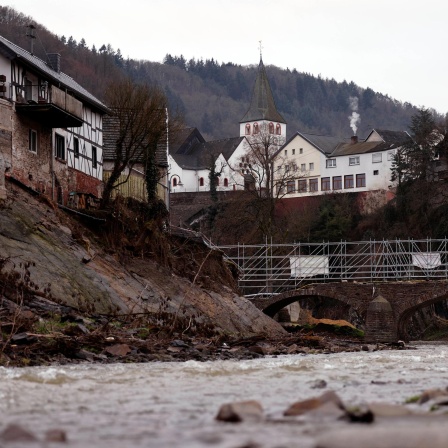 Blick auf die vom Jahrhunderthochwasser schwer getroffene Ortsgemeinde Schuld. Mehr als ein halbes Jahr nach der Flut im Ahrtal ist der Wiederaufbau zwar vorangeschritten. Aber noch immer sind manche Häuser zerstört und es führen stellenweise nur provisorische Brücken über die Ahr.
      
