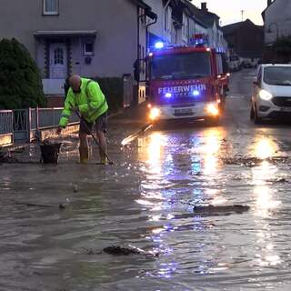 Einsatzkräfte arbeiten auf einer überfluteten Straße in der Gemeinde Grafschaft im Kreis Ahrweiler.