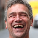 Ein breit lachender Mann vor neutralem Hintergrund