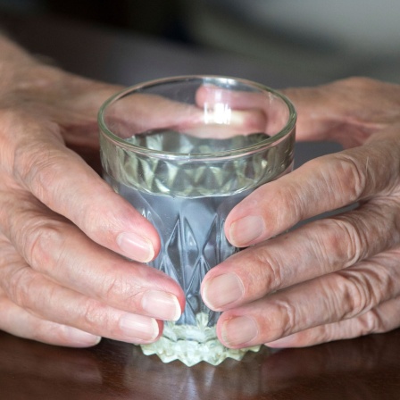 Ältere Person mit Glas in der Hand