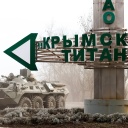 Ein Straßenschild bei dem Checkpoint Perekop an der ukrainischen Grenze weist den Weg zu der Titan-Anlage in Armyansk auf der Krim, neben dem Schild ein Panzer.