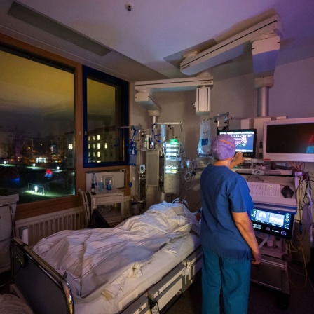 Eine Krankenpflegerin versorgt in einem Patientenzimmer eines abgetrennten Bereichs für Covid-19 Patienten einer Intensivstation des Klinikum Stuttgart, einen Covid-19-Patienten.