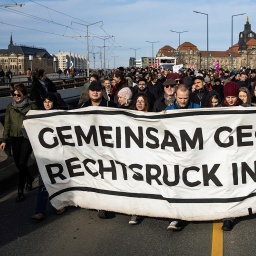 Hinter einem Plakat mit der Aufschrift "Gemeinsam gegen den Rechtsruck in Europa" stehen Demonstranten.