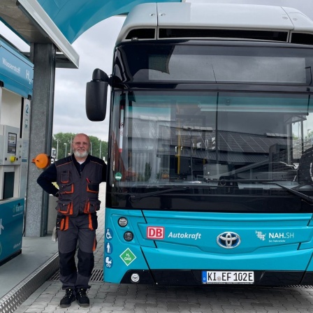 Sven Hensel, Busfahrer Autokraft steht neben einem Wasserstoffbus an der Wasserstofftankstelle in Niebüll.