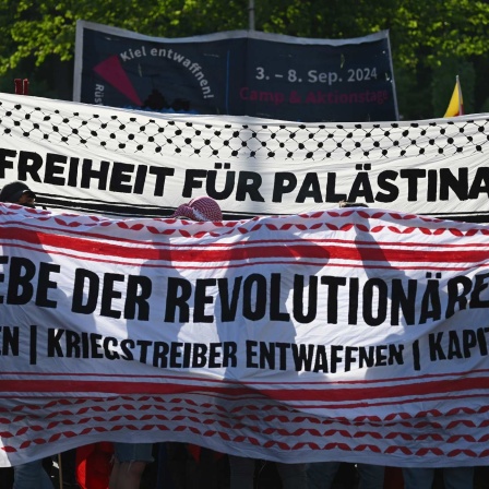 Teilnehmer der "Revolutionären 1. Mai-Demonstration" versammeln sich und halten Banner mit der Aufschrift "Freiheit für Palästina" und "Es lebe der revolutionäre 1. Mai".