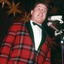 Schlagersänger Bill Ramsey in jüngeren Jahren im Jacket mit Schottenkaro und grüner Fliege singt auf der Bühne