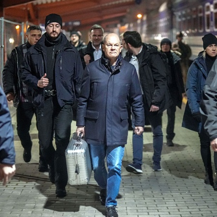 Bundeskanzler Olaf Scholz (SPD, M) geht in Begleitung von Sicherheitskräften auf dem Bahnhof der polnischen Grenzstadt Przemysl zum Sonderzug für die Fahrt in die ukrainische Hauptstadt Kiew.