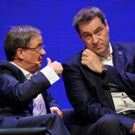 Nordrhein-Westfalens Ministerpräsident Armin Laschet (links) sitzt neben seinem bayerischen Amtskollegen Markus Söder und unterhält sich bei einer Veranstaltung 2019 in Münster mit ihm