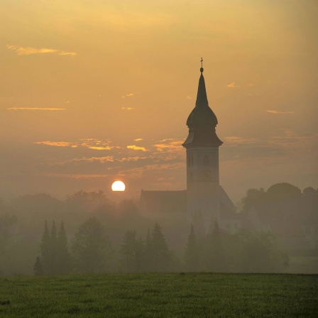 Sonnenaufgang in Rottenbuch hinter der Kirche Mariä Geburt, Kreis Weilheim-Schongau, Bayern